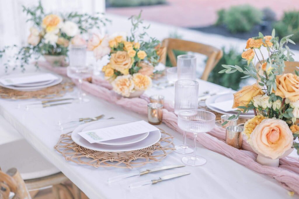 Wedding reception table featuring orange floral centerpieces and wedding menu cards