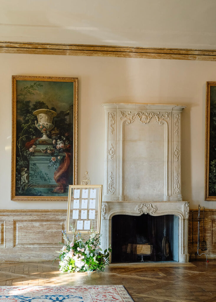 Elegant mansion entryway with seating chart display, fine art, and fireplace