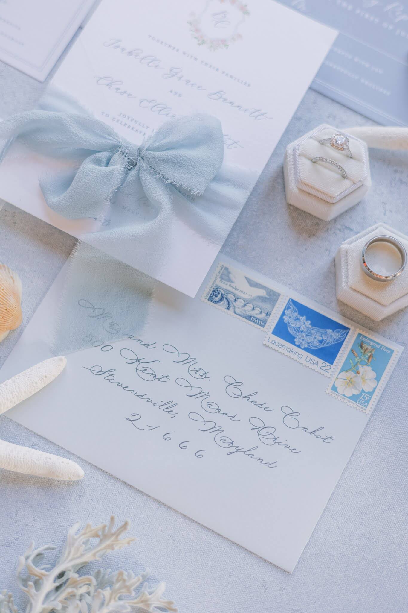 Light blue wedding invitation envelope with elegant calligraphy and vintage postage