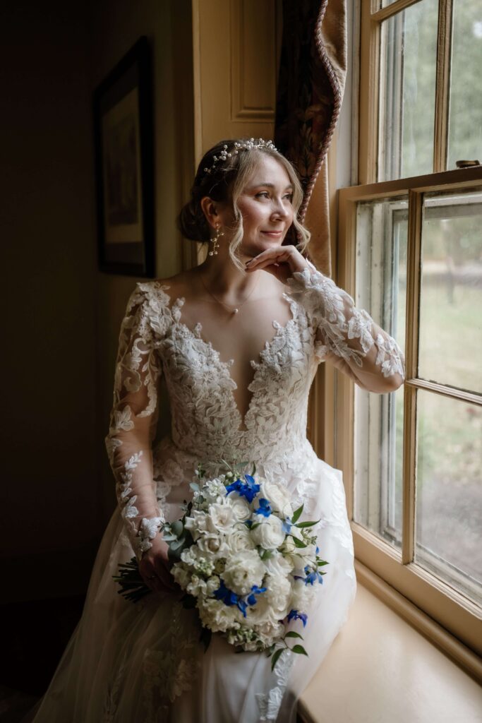 Bridal portrait smiling and looking out the mirror of the Joseph Ambler Inn