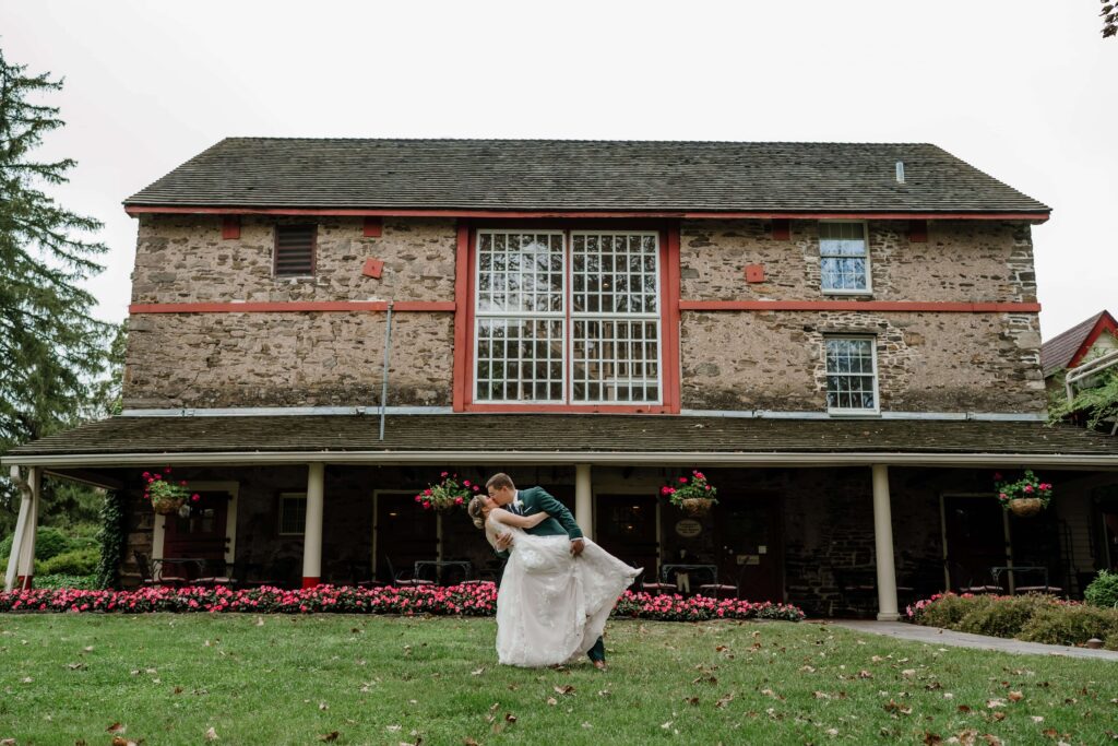 Bride and groom kissing in front of the Joseph Ambler Inn on their wedding day