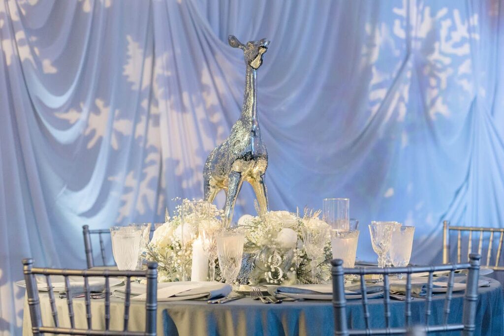 Elegant white and icy blue tablescape with crystal drinkware and silver deer sculpture