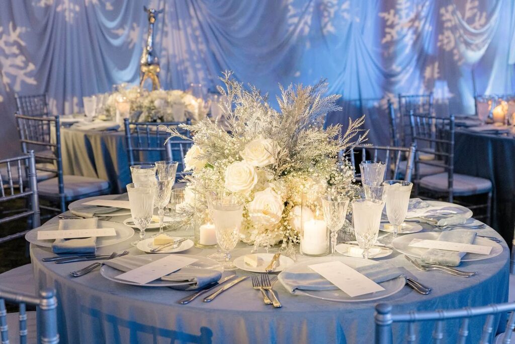 Elegant AACWP winter gala tablescape with an icy blue tablecloth, custom menu cards, and warm candlelight