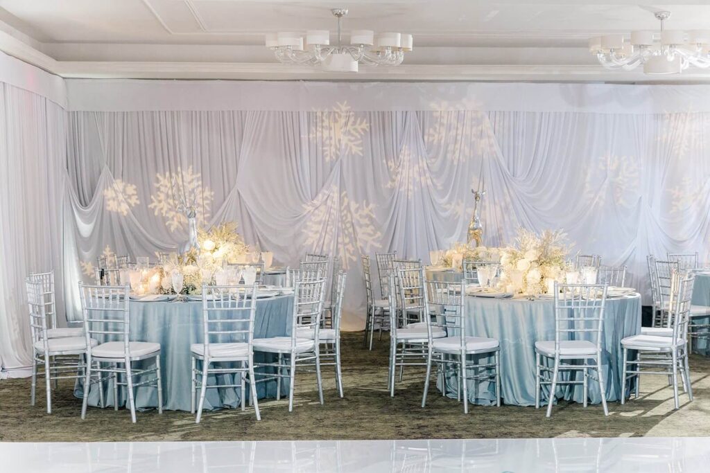 Elegant AACWP winter gala tables in a room with snowflakes projected onto white draping