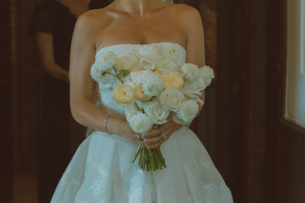 Bride carrying bouquet of white and light yellow flowers