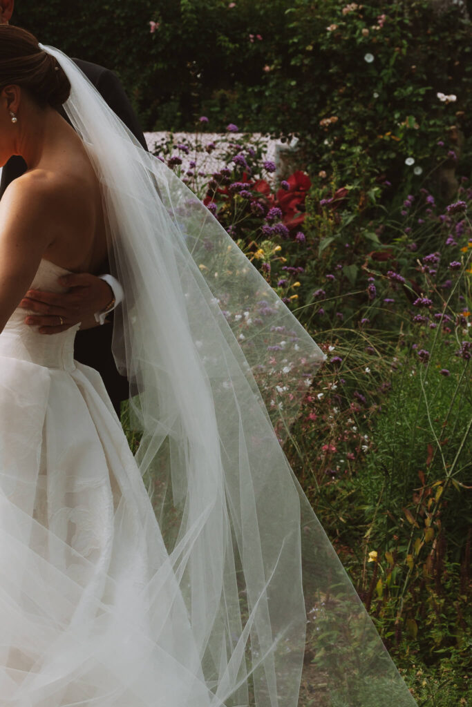 Details shot of the bride's veil while she is standing in a garden