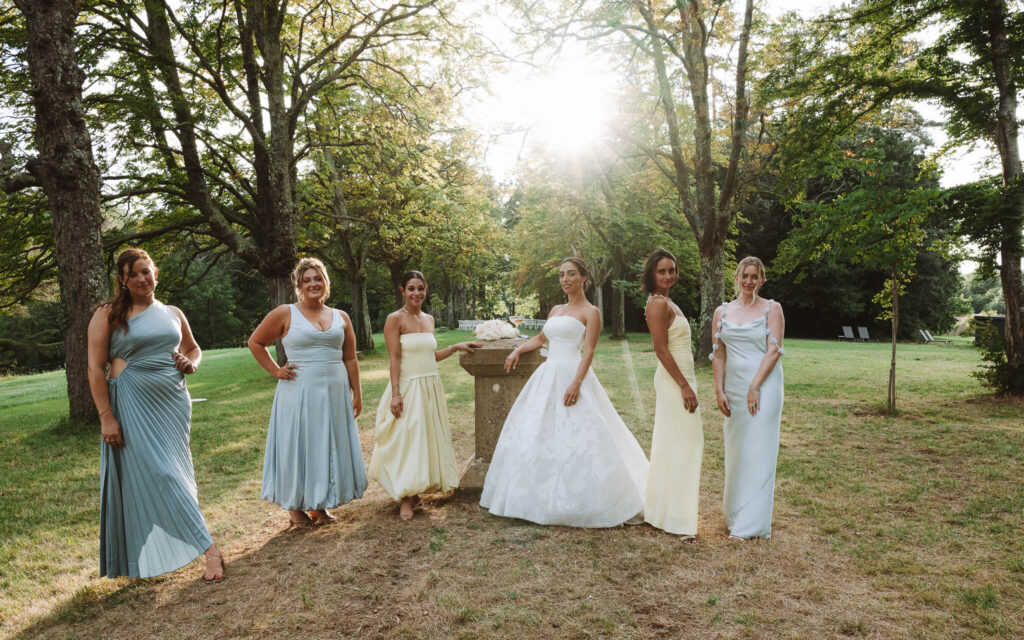 Bride in a shaded grove with bridesmaids, wearing light blue and yellow