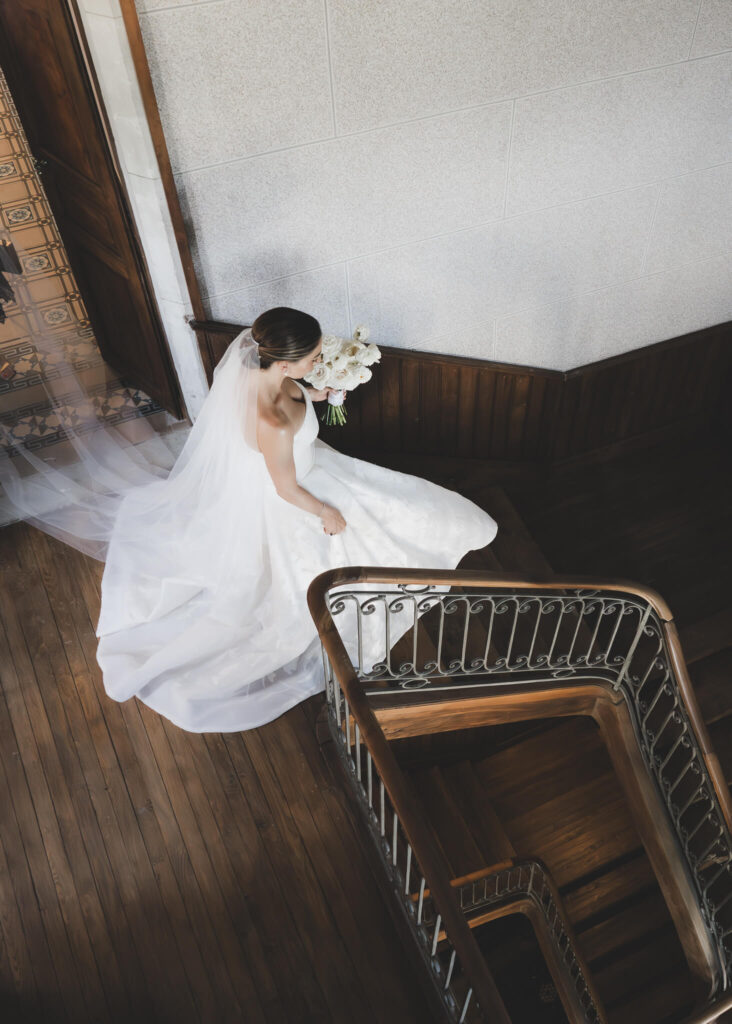 Bride descending staircase in Château de Sibra with her wedding bouquet