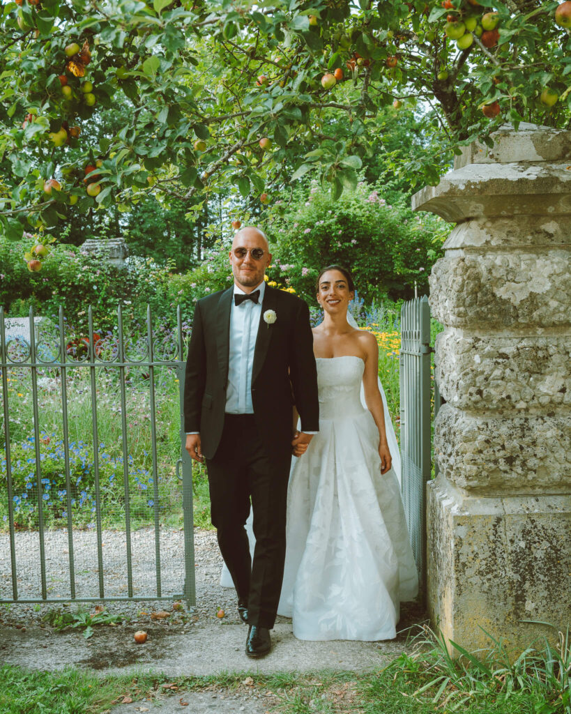 Bride and groom walking through the gates of a lush garden