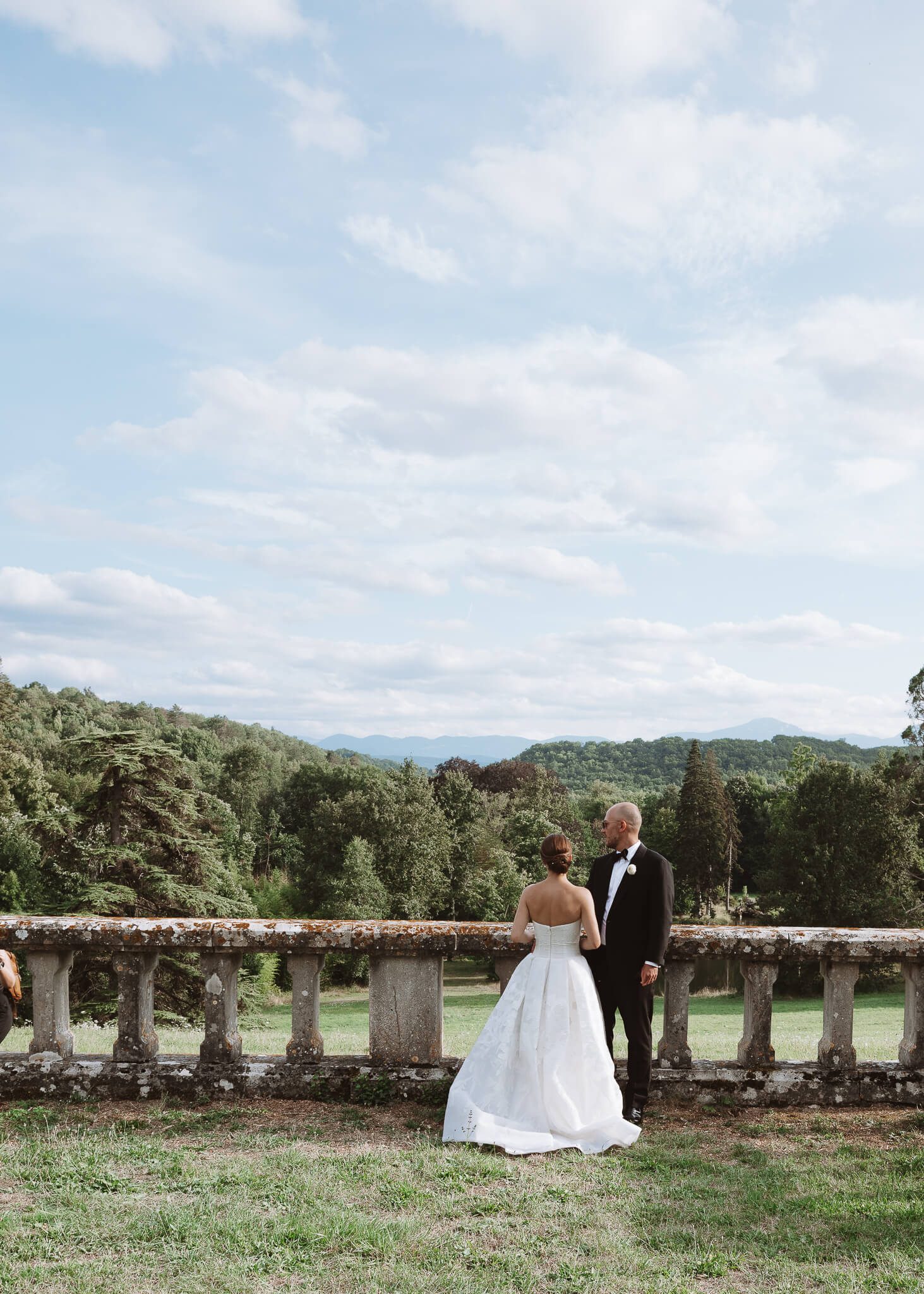 Bride and groom look over a stone fence at Château de Sibra