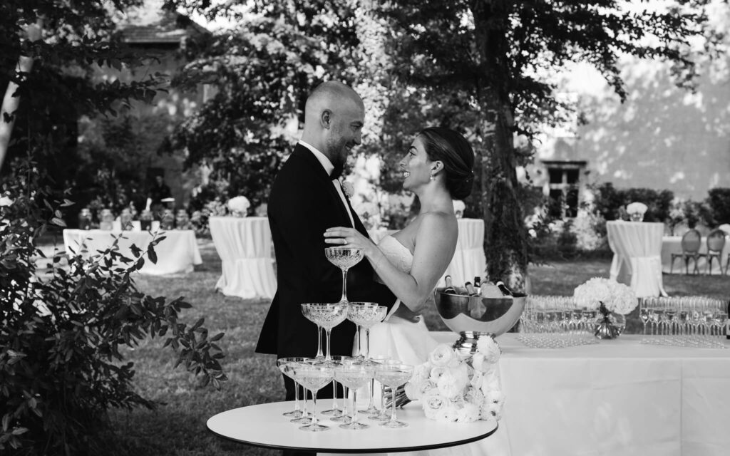 Bride and groom smile and embrace during an outdoor cocktail hour