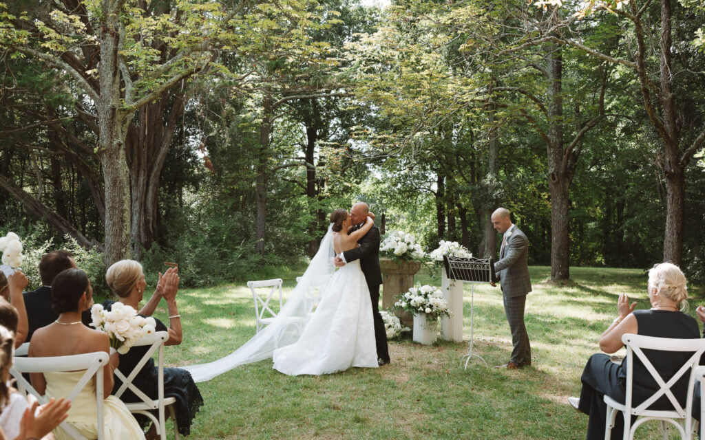 Bride and groom share their first kiss in a shaded grove at Château de Sibra during their wedding ceremony