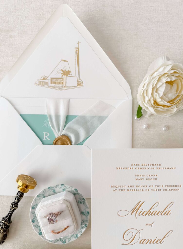Wedding invitation envelope featuring a line art illustration in gold of the wedding ceremony venue
