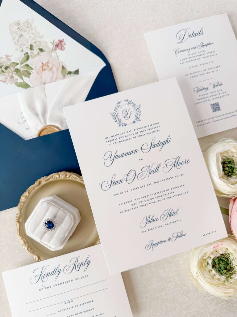 Formal navy and white wedding invitation with elegant script font and custom monogram and crest