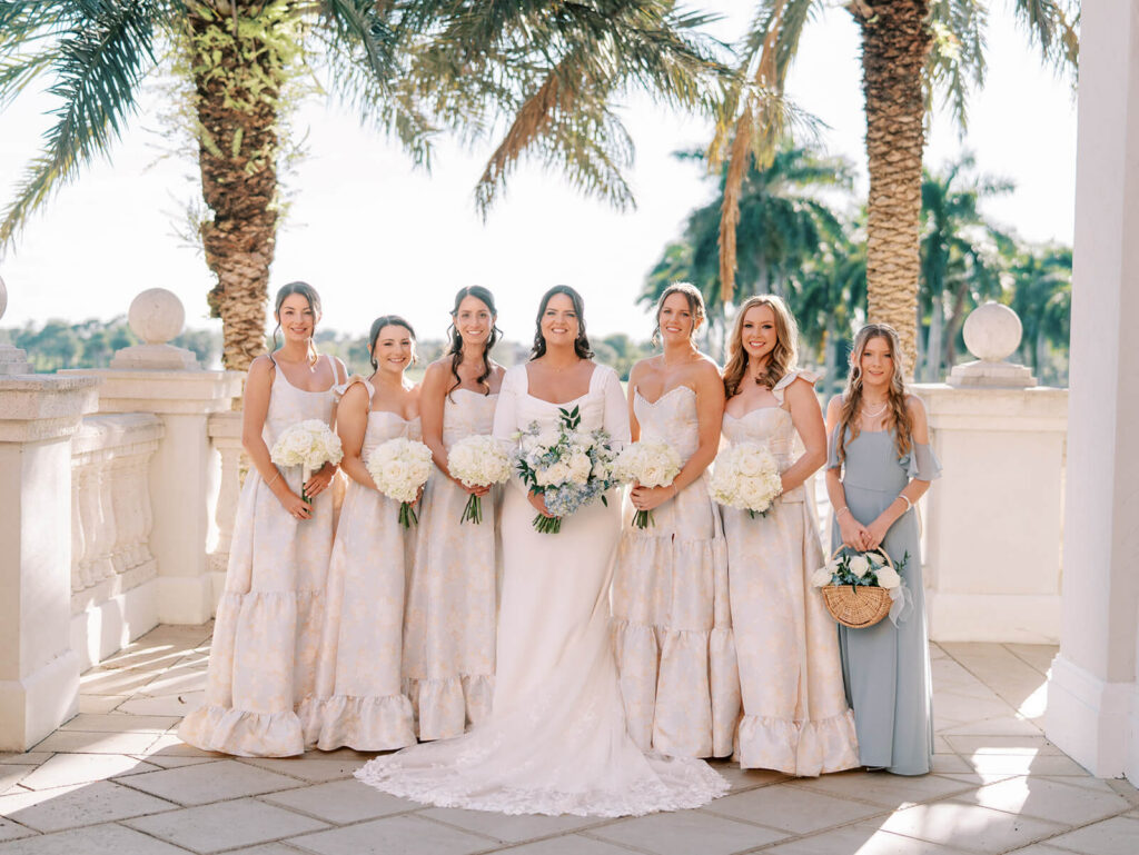 Bride with bridal party on an outdoor balcony surrounded by palm trees