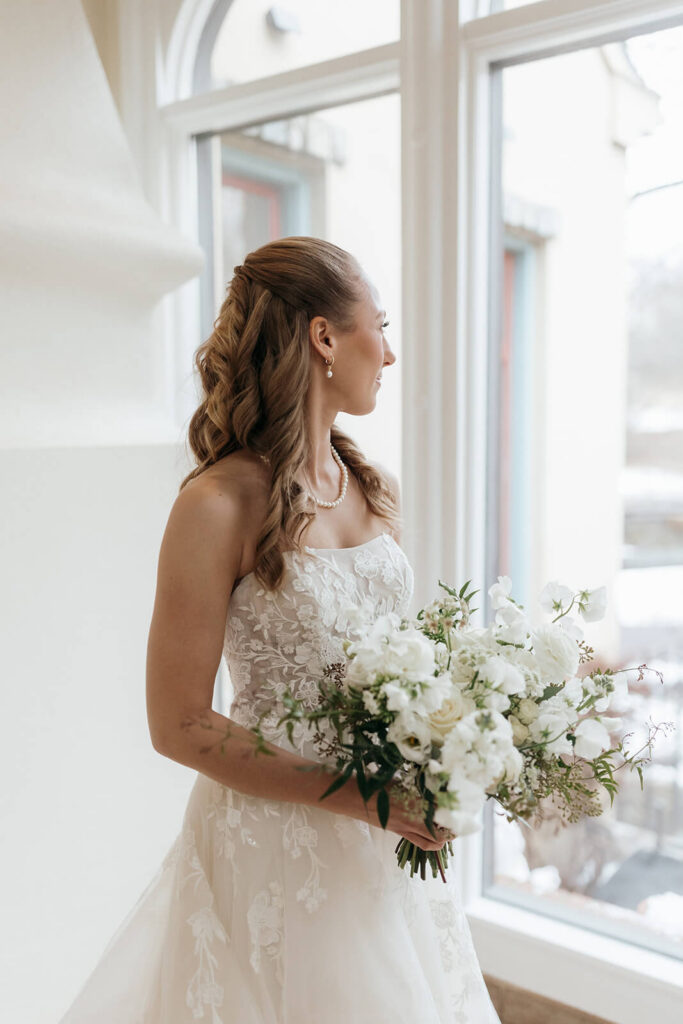Elegant portrait of the bride holding a white and green bouquet