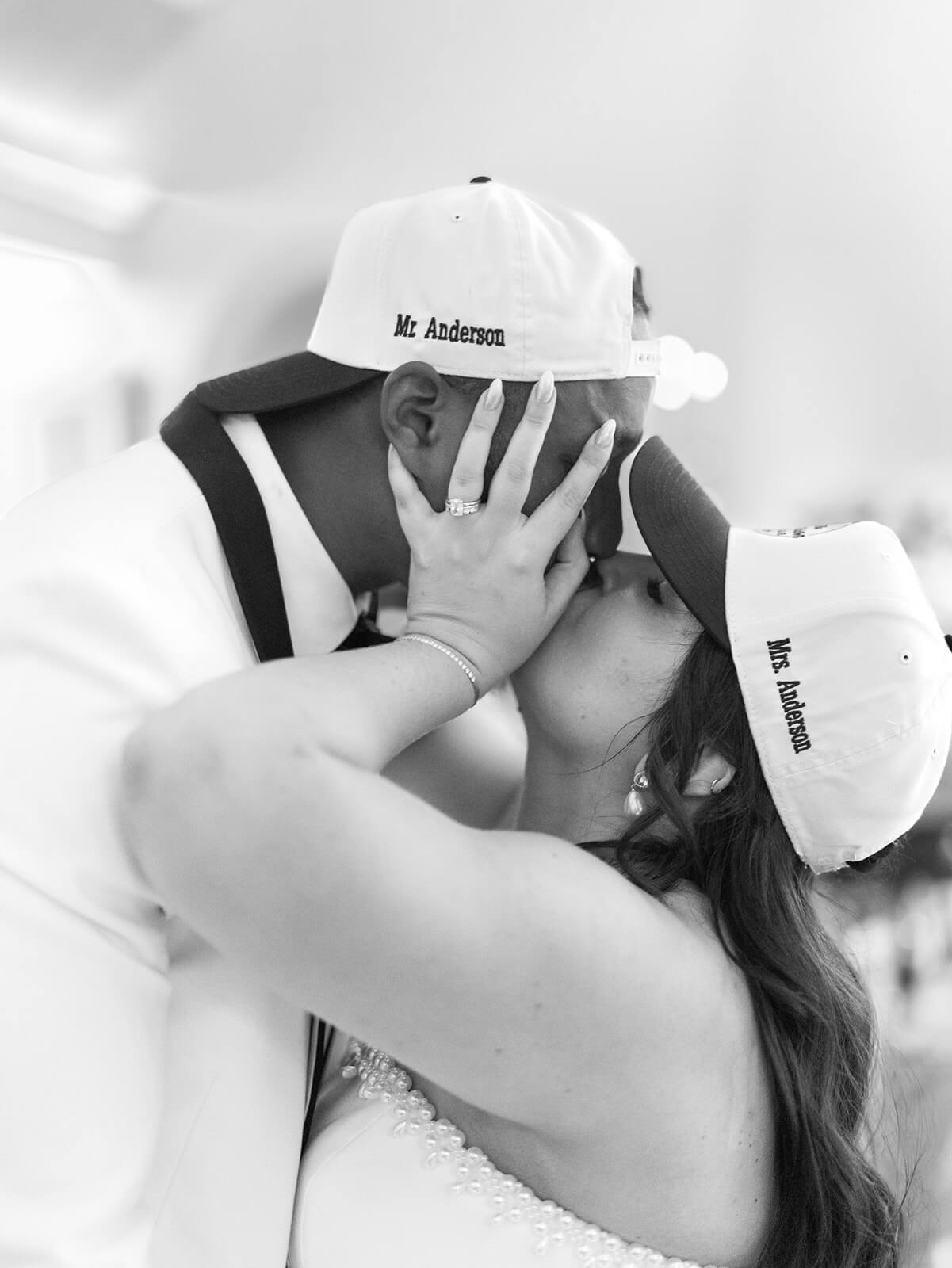 Bride and groom kiss while wearing custom embroidered hats
