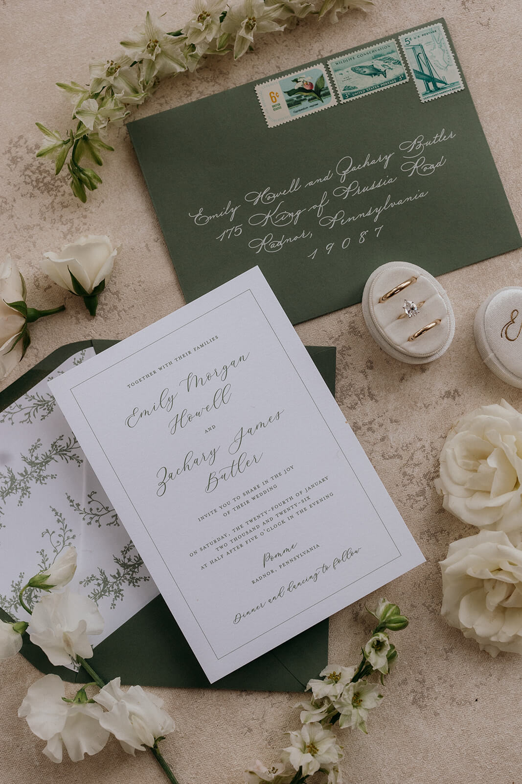 Elegant white and green wedding invitation with script font and greenery details