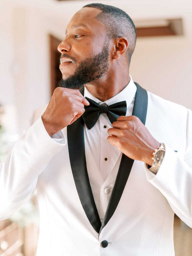 Portrait of groom adjusting bow tie