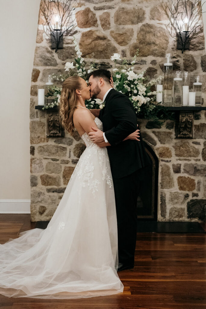 Bride and groom share their first kiss in front of the hearth at Pomme Radnor