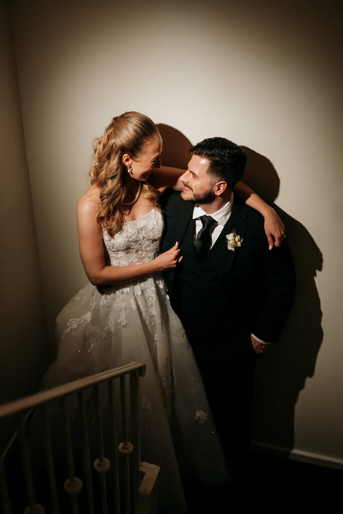 Bride and groom share a private moment in a stairwell as their wedding day ends