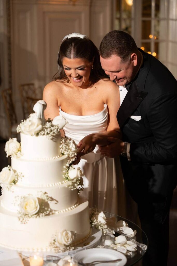 Bride and groom smile as they cut their wedding cake