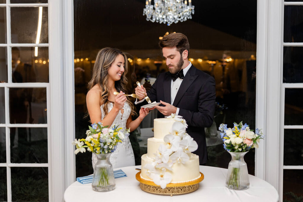 Bride and groom tasting their wedding cake: a three tiered cake adorned with orchids
