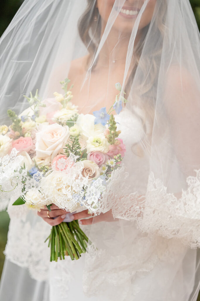 Bridal portrait featuring lacy veil and pastel bouquet