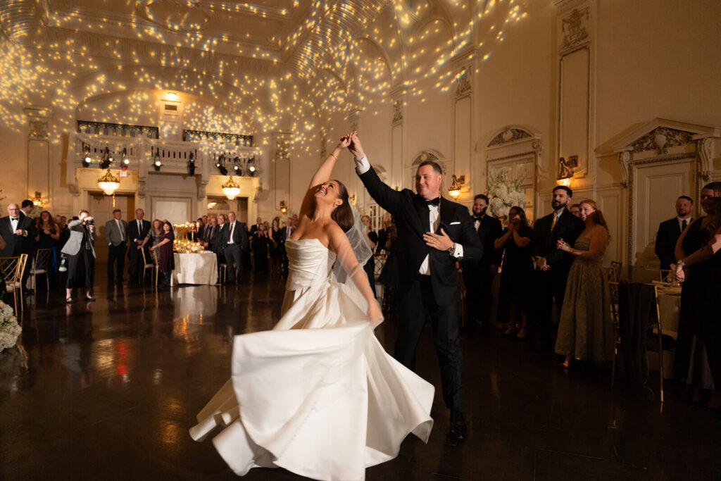 Groom twirls bride during their first dance as a married couple