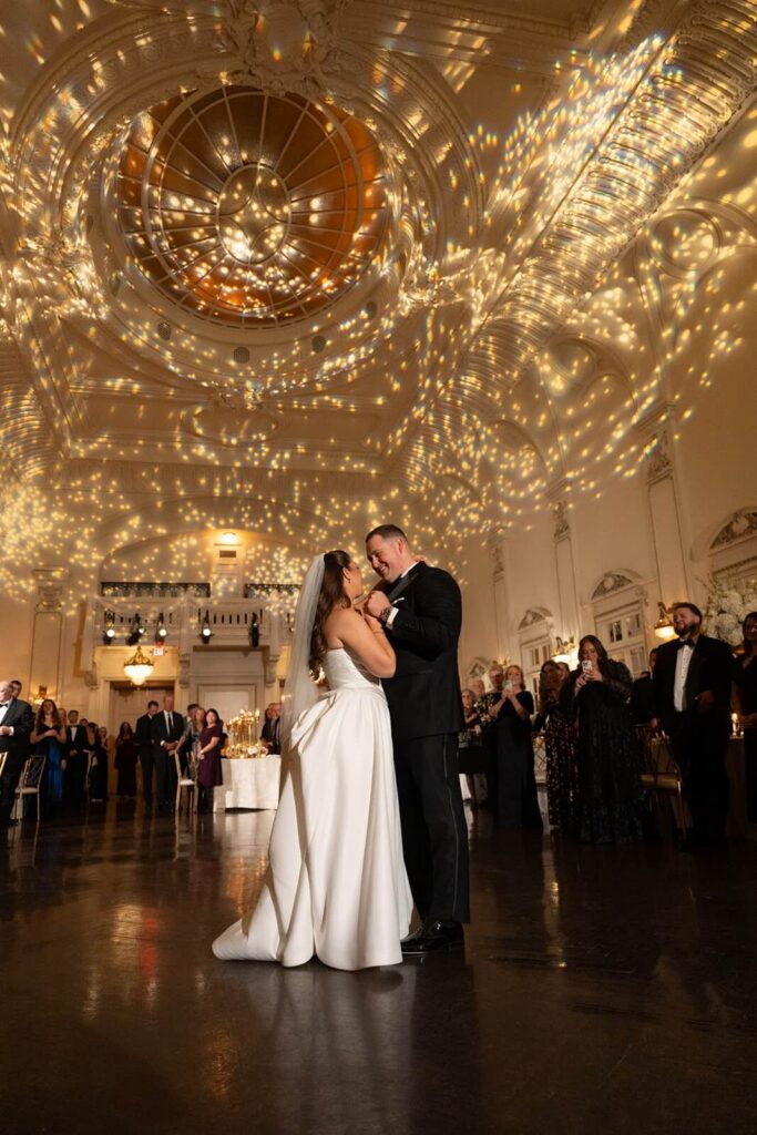 Bride and groom sharing their first dance as romantic uplighting creates a glittering design on the ceiling