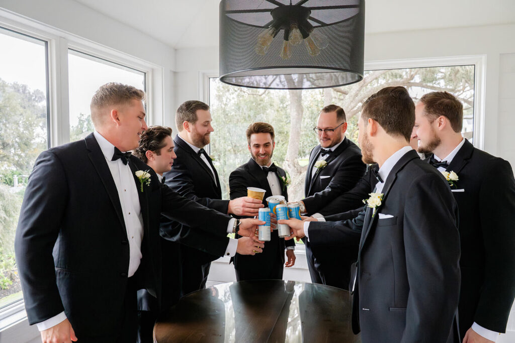 Groom and groomsmen clinking their drinks together on the wedding day