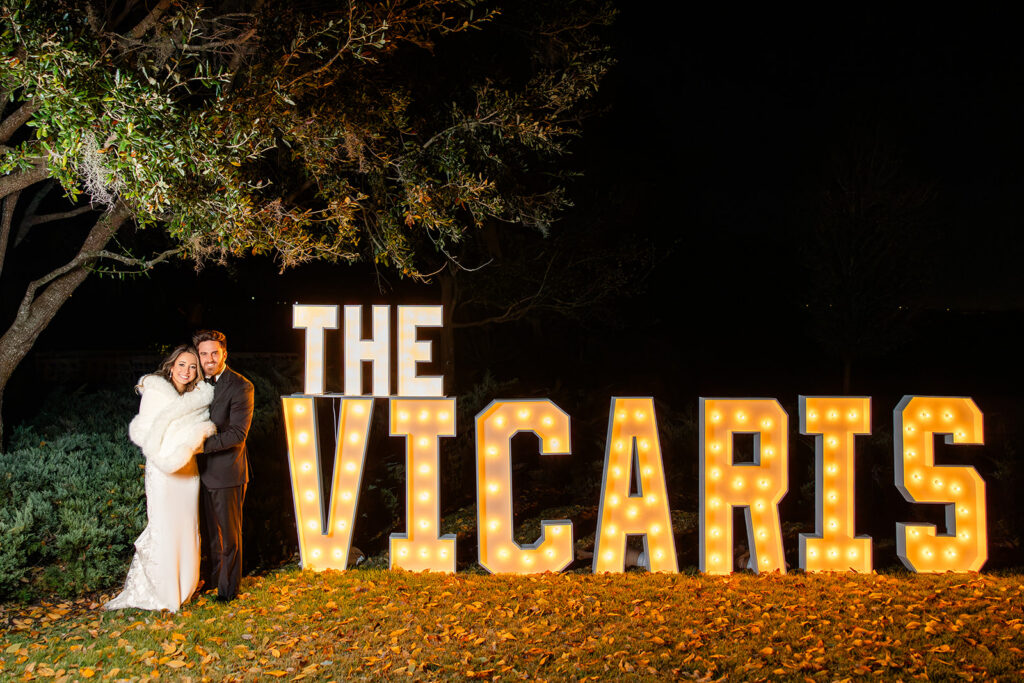 Bride and groom beside the marquee letters of their last name