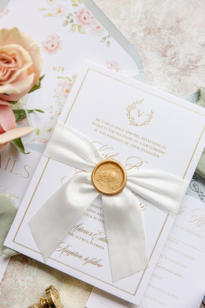 Custom wedding invitation card with gold foil press, custom monogram, gold wax seal, and silk ribbon