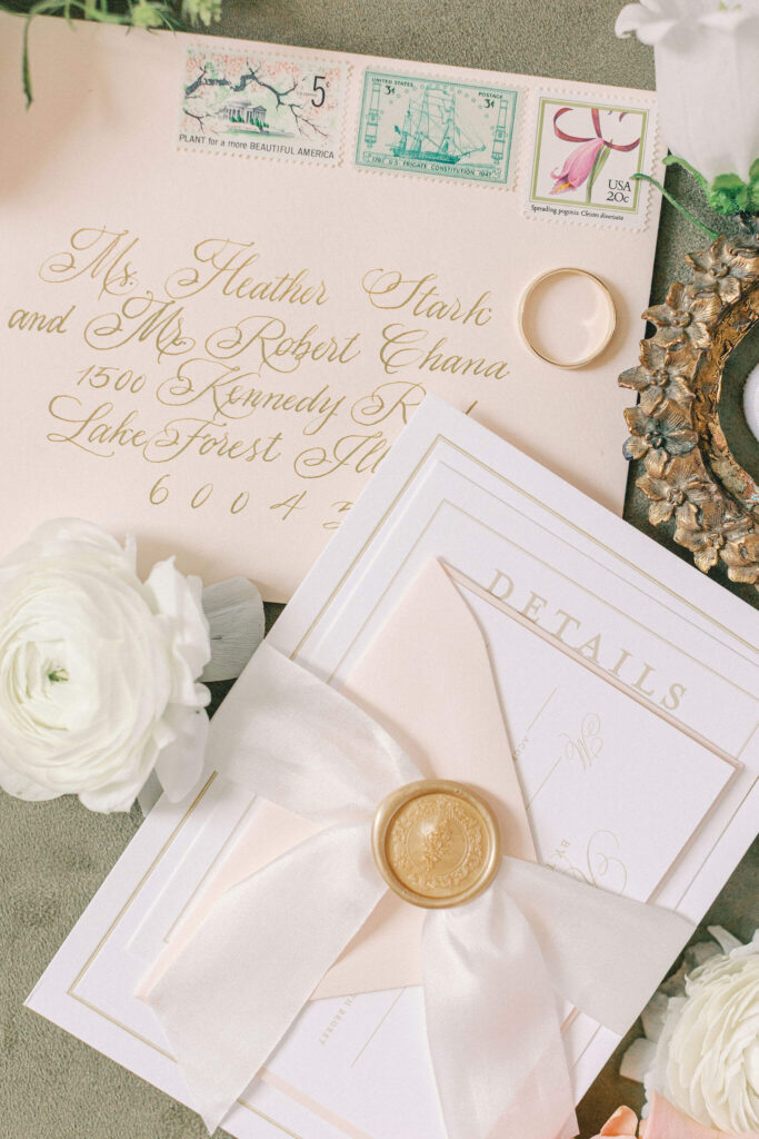 Elegant pink, white, and gold wedding invitation suite with calligraphy and vintage postage