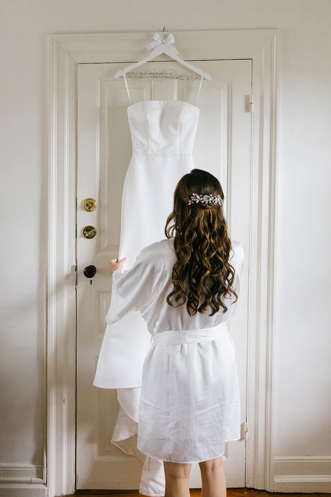 Bride admiring her wedding dress on its hanger