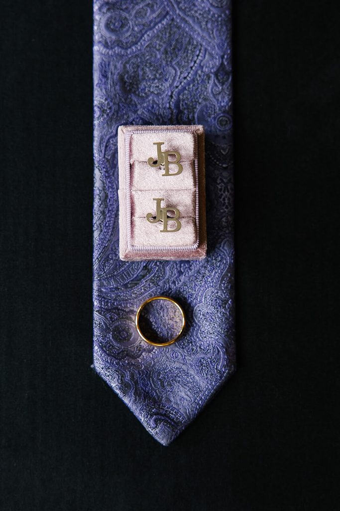 Silver cufflinks sitting on a purple tie
