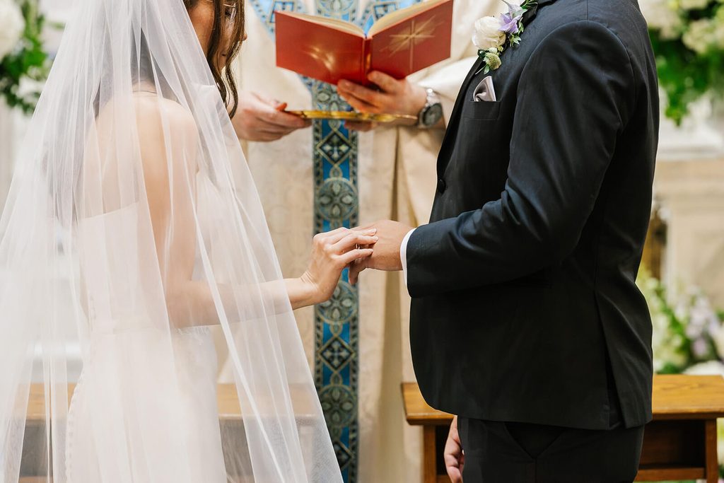 Bride placing ring on groom's finger during wedding ceremony